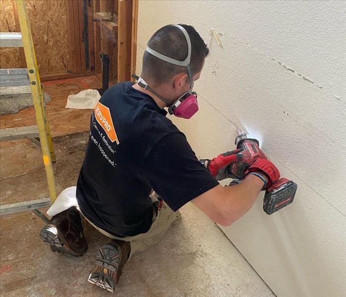 technician cutting a hole in the wall
