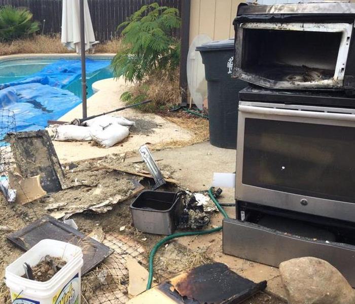 pool filled with water with fire damaged kitchen supplies and kitchen appliances in gold river home, fire damage sac nearby
