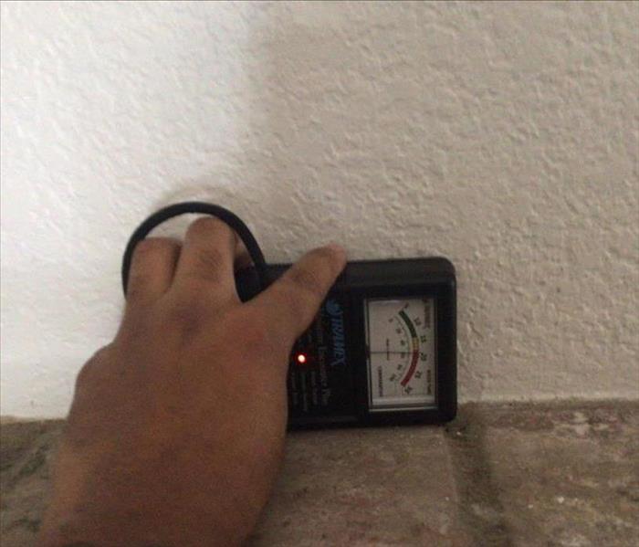 moisture meter reading wet drywall above fireplace